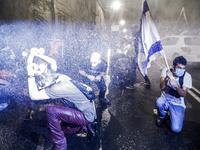 Israeli police spray protesters (clad in masks due to the COVID-19 coronavirus pandemic) with water cannon during an anti-government demonstration in Jerusalem, on July 18, 2020. Ahmad GHARABLI / AFP