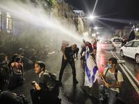 Israeli police spray protesters (clad in masks due to the COVID-19 coronavirus pandemic) with water cannon during an anti-government demonstration in Jerusalem, on July 18, 2020. Ahmad GHARABLI / AFP