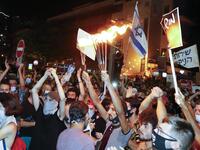 Israelis wearing protective face masks due to the COVID-19 coronavirus pandemic, take part in a demonstration on July 18, 2020, in Charles Clore Park in the Israeli coastal city of Tel Aviv to protest against the Israeli government and Prime Minister Benjamin Netanyahu for the broken promises made by the Israeli government during the Covid-19 pandemic. Israel's government said today it was imposing new restrictions to limit the spiraling spread of coronavirus.