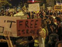 Israeli demonstrators lift placards during a rally against Prime Minister Benjamin Netanyahu outside his official residence in Jerusalem, on July 18, 2020, amid the coronavirus pandemic. Israeli police fired water cannons to disperse anti-government protests attended by thousands on Saturday, as public anger mounts over the handling of the coronavirus crisis. 