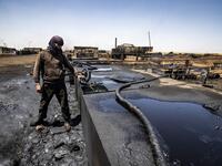 A man works at a makeshift refinery using burners to distill crude oil in the village of Bishiriya in the countryside near the town of Qahtaniya west of Rumaylan (Rmeilan) in Syria's Kurdish-controlled northeastern Hasakeh province, on July 19, 2020. DELIL SOULEIMAN / AFP