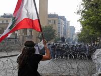 A Lebanese protester waves the national flag during clashes in downtown Beirut on August 8, 2020, following a demonstration against a political leadership they blame for a monster explosion that killed more than 150 people and disfigured the capital Beirut. ANWAR AMRO / AFP