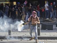 A Lebanese protester throws a tear-gas canister back at security forces in downtown Beirut on August 8, 2020, following a demonstration against a political leadership they blame for a monster explosion that killed more than 150 people and disfigured the capital Beirut. JOSEPH EID / AFP