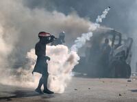 A topless protester wearing a gas mask uses a racket to volley back a tear gas canister during clashes with security forces in downtown Beirut on August 8, 2020, following a demonstration against a political leadership they blame for a monster explosion that killed more than 150 people and disfigured the capital Beirut. PATRICK BAZ / AFP