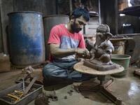 In this picture taken on August 11, 2020, an artisan prepares a clay idol of elephant headed Hindu god Ganesha at Muslim potter Yusuf Zakaria Galwani's workshop at Kumbharwada inside the Dharavi slums in Mumbai. After the coronavirus pandemic clobbered his pottery business, a Muslim artisan from India's largest slum turned to a Hindu god to revive his fortunes by making environmentally-friendly Ganesha idols for an upcoming festival. In Mumbai's Dharavi slum, Galwani worked alongside his two brothers to cre