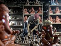 In this picture taken on August 11, 2020, Muslim potter Yusuf Zakaria Galwani inspects a clay idol of elephant headed Hindu god Ganesha at his workshop at Kumbharwada inside the Dharavi slums in Mumbai. After the coronavirus pandemic clobbered his pottery business, a Muslim artisan from India's largest slum turned to a Hindu god to revive his fortunes by making environmentally-friendly Ganesha idols for an upcoming festival. In Mumbai's Dharavi slum, Galwani worked alongside his two brothers to create 13-in