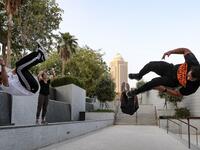 Hamzar Mekkaoui (R) , Achref Bejaoui (L) and a friend perform parkour, a sport that originated in France in the 1990s, which involves getting around urban obstacles with a fast-paced mix of jumping, vaulting, running and rolling, in the Qatari capital Doha, on August 11, 2020. Parkour, also known as free-running, has now found a small but committed following in Qatar despite evening temperatures that hover around 40 degrees Celsius (104 Fahrenheit) in summer and over-zealous security guards unfamiliar with 