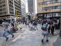 Demonstrators run for cover after clashes erupted during the fifth straight day of protests against police brutality in Bogota on September 13, 2020. Bogota's Mayor Claudia Lopez, apologized this Sunday for the abuses of the public force, in a ceremony that gathered relatives of the dead and wounded during the bloody protests that broke out five days ago against police brutality in Colombia. Juan BARRETO / AFP