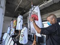 A gallery worker organizes white coats used by doctors fighting against COVID-19 and decorated by Panamanian artists, in Panama City, on September 26, 2020. More than 20 doctor's coats fighting against COVID-19 that were disinfected and painted by Panamanian artists will be auctioned off from October 1 to 4. The funds will go to 20 health centers. Luis ACOSTA / AFP