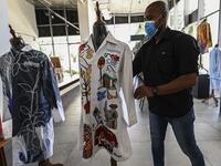 A gallery worker organizes white coats used by doctors fighting against COVID-19 and decorated by Panamanian artists, in Panama City, on September 26, 2020. More than 20 doctor's coats fighting against COVID-19 that were disinfected and painted by Panamanian artists will be auctioned off from October 1 to 4. The funds will go to 20 health centers. Luis ACOSTA / AFP