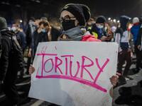 A protestor blocked by riot police guarding the house of Jaroslaw Kaczynski, leader of Poland's ruling Law and Justice party (PIS)holds a poster reading "torture" during a demonstration against a decision by the Constitutional Court on abortion law restriction,in Warsaw on October 23, 2020. Wojtek RADWANSKI / AFP