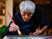 This photograph taken on October 8, 2020 shows 89-year-old Vietnamese artist Mong Bich painting at her house in Bac Ninh province, east of Hanoi. Bich specialises in silk paintings of daily life and ordinary people, women in particular, and ploughed a lonely furrow during many years of war when artists were steered towards the army or frontline workers as subjects. Manan VATSYAYANA / AFP