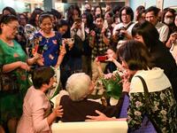This photograph taken on October 22, 2020 shows guests greeting 89-year-old Vietnamese artist Mong Bich during the opening of her first solo exhibition at the French Cultural Centre in Hanoi. Bich specialises in silk paintings of daily life and ordinary people, women in particular, and ploughed a lonely furrow during many years of war when artists were steered towards the army or frontline workers as subjects. Manan VATSYAYANA / AFP