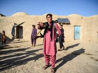 In this photo taken on September 27, 2020, a policeman (C) holding weapons stands guard in the courtyard of a house at Deh Qubad village in Maiwand district of Kandahar province. The dry and dusty village of Aziz Abad in Maiwand district sits on the frontline of Afghanistan's war and is currently under government control -- but only just. WAKIL KOHSAR / AFP