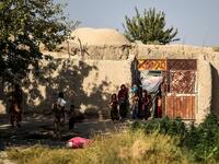 In this photo taken on September 27, 2020, children gather at the entrance of a house at Deh Qubad village in Maiwand district of Kandahar province. The dry and dusty village of Aziz Abad in Maiwand district sits on the frontline of Afghanistan's war and is currently under government control -- but only just. WAKIL KOHSAR / AFP