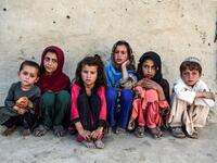 In this photo taken on September 27, 2020, children sit in front of a house at Deh Qubad village in Maiwand district of Kandahar province. The dry and dusty village of Aziz Abad in Maiwand district sits on the frontline of Afghanistan's war and is currently under government control -- but only just. WAKIL KOHSAR / AFP