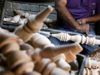 A carpenter shaves a piece of wood to make a narguileh (water pipe) at his workshop in Iraq's central holy city of Karbala on October 21, 2020. MOHAMMED SAWAF / AFP