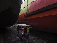 In this picture taken on November 16, 2020 dockyard workers carry a metal sheet during maintenance works for a ship on the banks of the Buriganga River in Char Kaliganj on the outskirts of Dhaka. Rivers are the lifeblood of the delta nation of 168 million people where much of the low-lying land is accessed via boat, with Bangladesh's strong economic growth of recent years fuelling more investments in new and bigger ships. Munir UZ ZAMAN / AFP
