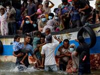 This photo taken on June 25, 2020 shows six-year-old daughter Nosmin Fatima (bottom L) being carried off a boat as she and her mother Majuma land with other Rohingya migrants in Lhokseumawe in North Aceh Regency. Weeks after a funeral for the wife and daughter he thought had died at sea while trying to sail to him, Nemah Shah was stunned when he saw online images of them emerging from a refugee boat in Indonesia. MUNIR UZ ZAMAN / AFP