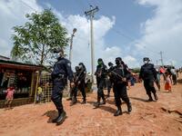 In this photograph taken on October 7, 2020, Rapid Action Battalion (RAB) personnel patrol along a street in Jamtoli refugee camp for Rohingyas in Ukhia. Boatloads of Rohingya landing across Southeast Asia are victims of complex human trafficking networks run by a dizzying web of players, from crime bosses and corrupt cops to poor fishermen, rickshaw drivers and even Rohingya themselves. Munir UZ ZAMAN / AFP