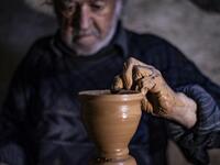 Syrian-Armenian potter Misak Antranik Petros uses an ancient pottery wheel to churn different types of pots at his workshop located inside an ancient mud-brick house near the city of Qamishli in Syria's northeastern Hasakeh province, on December 19, 2020. Petros was only a teenager when he had to take over for his sick father and become the main potter of the family. He has since become a master of the craft, and is keen to pass his skills on.  Delil SOULEIMAN / AFP