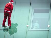 A man dressed as a Santa Claus waves to a child as he descends from the roof of the paediatric clinic in Ljubljana, Slovenia on December 21, 2020. Jure Makovec / AFP