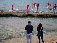 Lebanese people dressed in Santa Claus outfits ride on standup paddles in Lebanon's northern coastal city of Batroun on December 22, 2020. Ibrahim CHALHOUB / AFP