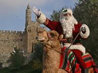 Issa Kassissieh, better known as the Santa Claus of Jerusalem, rides a camel on December 22, 2020 outside Jerusalem's Old City walls. MENAHEM KAHANA / AFP