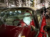Rob Holtzapfel, a member of a vintage car group dressed as Santa Claus, sits in a 1959 Cadillac along a street lined with Christmas-themed light decorations in Marunouchi district in Tokyo on December 25, 2020. Philip FONG / AFP
