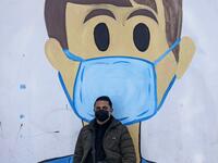 A Palestinian man sits in front of a coronavirus mural as part of the COVID-19 awareness campaign, in Khan Yunis in the southern Gaza Strip on January 20, 2021. SAID KHATIB / AFP