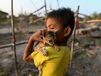 This photo taken on January 11, 2021 shows a Chin child playing with his cat in Bethel village in Hmawbi, on the outskirts of Yangon, where hundreds of members of the Chin ethnic community have settled after being displaced by fighting between Myanmar's military and the Arakan Army in the country's north.  Ye Aung THU / AFP