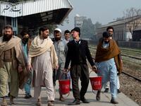 In this picture taken on February 9, 2021, street actor Usman Khan (2nd R), dressed up as silent film star Charlie Chaplin, performs at a train station in the Pakistan's northwestern city of Peshawar. Wearing a bowler hat and familiar toothbrush moustache, Pakistan's Usman Khan darts through traffic swinging a cane, teasing motorists and shopkeepers for laughs and a few rupees with a Charlie Chaplin impersonation that has become a viral sensation.  Abdul MAJEED / AFP