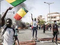 Protesters wave the Senegalese national flag during a protest in Dakar on March 8, 2021, after the country's opposition leader Ousmane Sonko was charged with rape. Usually considered a beacon of stability in a volatile region, deadly clashes between opposition supporters and security forces have rocked the West African state. JOHN WESSELS / AFP