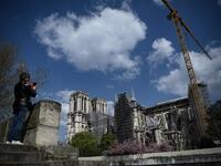 A woman takes pictures of Notre-Dame de Paris cathedral