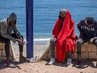 Subsaharian migants sit on a sea wall in the northern town of Fnideq as they attempt to cross the border from Morocco to Spain's North African enclave of Ceuta on May 19, 2021. Spain stepped up diplomatic pressure on Rabat as its prime minister flew into Ceuta, vowing to "restore order" in the North African enclave after a record 8,000 migrants reached its beaches from Morocco