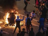 Migrants burn a skip during clashes with Moroccan riot police in the northern town of Fnideq, close to the border between Morocco and Spain's North African enclave of Ceuta on May 19, 2021. Migrants were still trying to cross from Morocco into the Spanish enclave of Ceuta on May 19, 2021, after a record 8,000 people poured over the border this week, escalating tensions between Rabat and Madrid. Some 5,600 migrants had already been sent back, Madrid said
