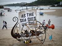 A boat sculpture with the words 'As the sea dies, we die' written on the sail is pictured during an Extinction Rebellion climate change protest on the beach in St Ives, Cornwall on June 11, 2021, on the first day of the three-day G7 summit being held from 11-13 June. G7 leaders from Canada, France, Germany, Italy, Japan, the UK and the United States meet this weekend for the first time in nearly two years, for the three-day talks in Carbis Bay, 