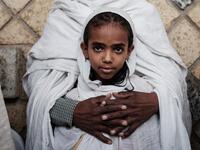 An 8-year-old girl Ethiopian Orthodox devote is held by her father as they attend the Saint Michael's anniversary celebration at St. Michael church in Mekele, the capital of Tigray region, Ethiopia