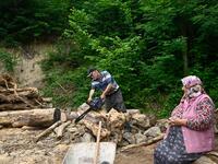 A villager saws wood as a woman looks on in Ikizdere in Rize Province in the Black Sea region of Turkey on June 7, 2021. A government-friendly company plans to extract 20 million tons of stone from a quarry in the northeastern town of Ikizdere for one of President Recep Tayyip Erdogan's latest development projects. The locals are rising up in protest, challenging the government and its priorities in a region dear to the domineering Turkish leader's heart. 