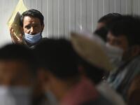 People wait to process a biometric registration to submit their passport applications at an office in Kabul on July 25, 2021. Dozens begin lining up at the passport office in Kabul before dawn most days, and by eight in the morning the queue already stretches for a good hundred metres.