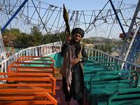 Taliban fighter carrying a rocket propelled grenade (RPG) launcher stands on pirate ship ride in a fairground at Qargha Lake on the outskirts of Kabul. "This is Afghanistan!" a Taliban fighter shouts on the pirate ship ride at a fairground in western Kabul, as his armed comrades cackle and whoop on board the rickety attraction. (Photo by WAKIL KOHSAR / AFP) / TO GO WITH: AFGHANISTAN-CONFLICT-FAIRGROUND, SCENE BY JAMES EDGAR - TO GO WITH: Afghanistan-conflict-fairground, SCENE by James EDGAR