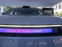 The four-door electric car appears more ready for production now sleeker and more advanced starting with a reimagined front that highlights its modern technological character. The front bumper features a sporty black strip at the bottom, along with an illuminated logo and a full-width light strip that merges with the uniquely shaped headlights.