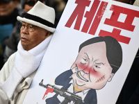 A man carrying a placard with a comic depicting South Korea's impeached president Yoon Suk Yeol marches during an anti-Yoon rally in Seoul on January 3, 2025. 