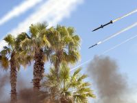 صواريخ باليستية في السماء على خلفية أشجار النخيل، مع آثار إطلاق الصواريخ…