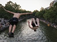 أشخاص يقفزون في قناة مائية هرباً من موجة الحر الشديدة وسط ارتفاع درجات الحرارة وتحذيرات من مخاطر الغرق