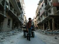 A Syrian boy pulls a cart with items collected amidst debris of destroyed buildings in Douma, in the rebel enclave of Eastern Ghouta on the outskirts of Damascus on Mar. 12, 2018. (HASAN MOHAMED / AFP)