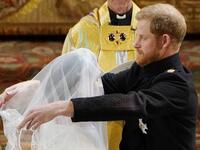 Britain's Prince Harry, Duke of Sussex (R) removes the veil of US actress Meghan Markle (L) as they stand at the altar together before Archbishop of Canterbury Justin Welby in St George's Chapel, Windsor Castle, in Windsor, on May 19, 2018 during their wedding ceremony. 
Owen Humphreys/ AFP