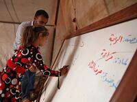 A Syrian child who fled with her family from the northern countryside of Hama, writes on the borad in a classoom at the makeshift school of "Zuhur al-Mustaqbal" Aaref WATAD / AFP