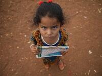 A Syrian child who fled with her family from the northern countryside of Hama, holds a book in the yard of the makeshift school of "Zuhur al-Mustaqbal" (in Arabic "Flowers of the Future") in al-Jeneinah camp for displaced people in the village of Atme, in Syria's mostly rebel-held northern Idlib province, on October 1, 2018. Aaref WATAD / AFP