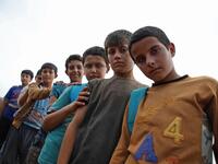 Syrian children who fled with their families from the northern countryside of Hama, pose in the yard of the makeshift school of "Zuhur al-Mustaqbal" (in Arabic "Flowers of the Future") in al-Jeneinah camp for displaced people in the village of Atme, in Syria's mostly rebel-held northern Idlib province, on October 1, 2018. Aaref WATAD / AFP